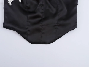 Detailansicht aus schwarzem Satin mit feiner weißer Spitzenverzierung am Saum des Tops