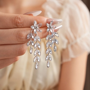 Close-up of elegant silver floral tassel earrings with sparkling crystals on a model
