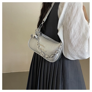 Detail of silver metallic crossbody bag with chain strap and sphere charm on model