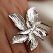 Close-up of a silver floral adjustable ring with layered petals and textured metal finish