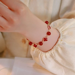 Elegant red agate beaded bracelet with gold quatrefoil clovers for women on wrist