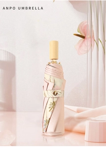 Folded pale pink sun umbrella with wooden handle and palm leaf pattern strap