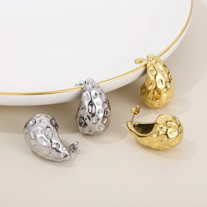 Macro detail of teardrop earrings with hammered texture in gold and silver finish