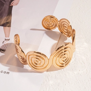 Detailed view of wide gold spiral metal cuff bracelet with a polished textured finish