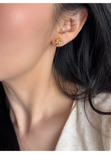 Close-up of elegant gold flower stud earring with pearls and diamonds on model ear