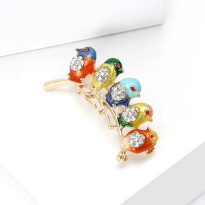 Detail of colorful enamel birds brooch with sparkling crystals on a golden branch