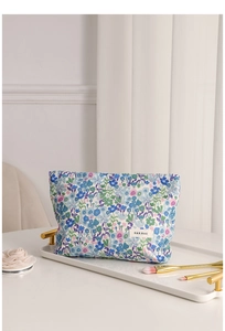 Detalle de neceser floral para maquillaje con pinceles en una elegante bandeja blanca