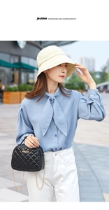 Detail of a chic black quilted crossbody bag with a gold chain strap and elegant blue shirt
