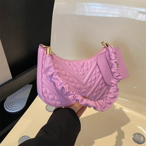 Detail of purple quilted shoulder bag featuring ruffled handle and gold hardware