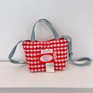 Detailed view of red and white checkered plaid mini tote bag with denim straps and logo label