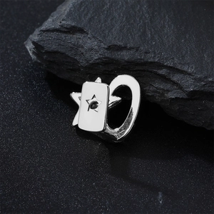 Macro shot of a silver star-shaped hip hop grillz accessory on a black mineral rock