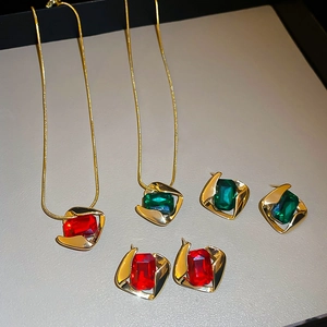 Detail view of gold necklaces and earrings set with red and green rectangular gemstones