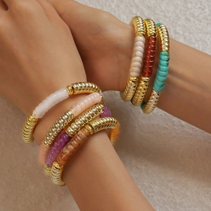 Gros plan de bracelets géométriques en acrylique coloré empilés sur le poignet d'un modèle