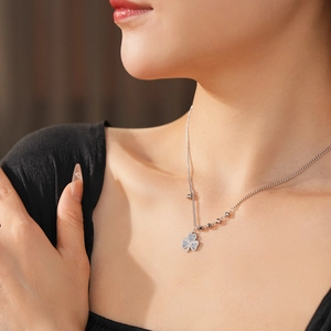 Detail view of silver clover heart pendant necklace with shimmering crystals on model neck