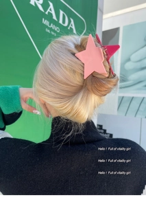 Star-shaped matte claw clip with pink color blocking on blonde braided hair bun