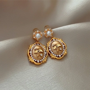 Detailed macro view of vintage ginkgo leaf earrings with pearls and zircons