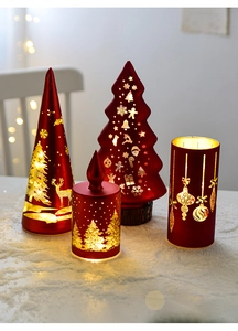 Close-up of glowing glass Christmas tree candles with warm LED lights and faux snow