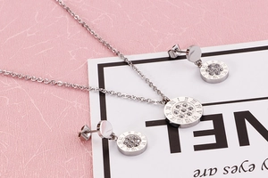 Detail of silver circular pendant and earrings set with Roman numerals and zircons