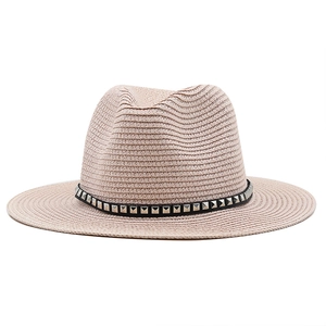 Detail of light beige straw fedora hat featuring a black band with silver square studs