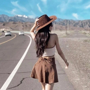 Cappello da cowboy marrone a tesa larga con outfit coordinato davanti a montagne innevate