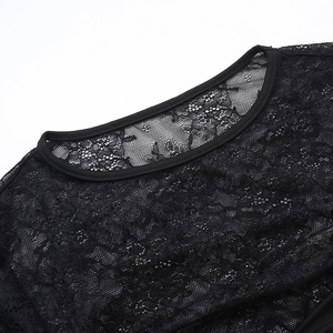 Détail du tissu en dentelle noire montrant des motifs floraux et les coutures de l'encolure