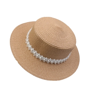 Detail of the woven straw texture and delicate pearl lace trim on a khaki boater hat