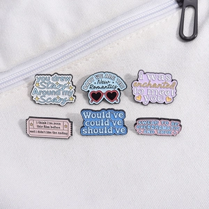 Close-up of six colorful enamel quote pins on a white canvas background