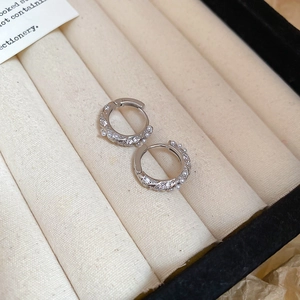 Macro shot of silver hoop earrings with zircon and pearls in a velvet jewelry box