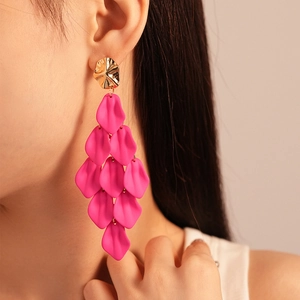 Close-up of rose red acrylic petal tassel earrings worn by a model in warm light