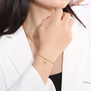 Set bracciale e collana a sfere dorate con ciondolo albero della vita su modella elegante