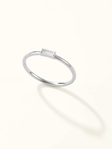 Detail of minimalist silver ring with clear baguette-cut gemstone on light background