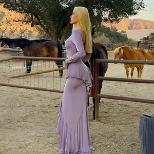 Side view of purple long-sleeved dress with ruffle details in an outdoor setting