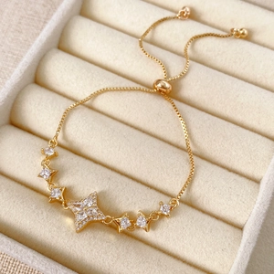 Detailed close-up of a gold star bracelet with cubic zirconia in a beige jewelry box