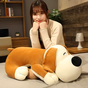 Close-up of a large brown and white plush puppy toy being held in a cozy home setting