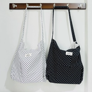 Detail of floral canvas tote bags in black and white polka dots on wooden hooks