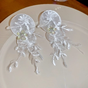 Détails des boucles d'oreilles en dentelle blanche brodée avec fleurs et perle centrale