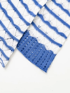 Detail aus weiß-blau gestreiftem Strickstoff mit wellenförmigem Lochmuster-Häkeldesign