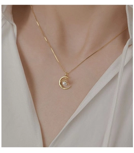 Close-up of pearl moon pendant necklace worn by model for elegant style display