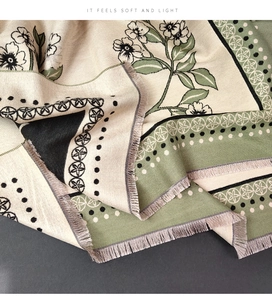 Detail of floral cashmere-like scarf with green leaf print and delicate fringe edges