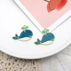 Close-up of a blue whale pendant with gold edges and green water spray for DIY jewelry