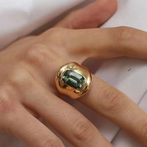 Vintage style gold ring featuring a rectangular cut green gemstone on model's hand