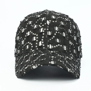Détail de la casquette en denim noir avec paillettes argentées et motifs déchirés