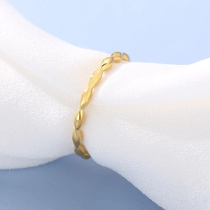 Macro shot of gold minimalist beaded band ring on white silk with light blue background