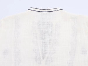 Detail of vintage linen shirt featuring white fabric and dark blue cross-stitch embroidery