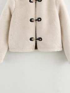 Détail de la veste en fausse fourrure avec bordure en cuir noir et boucles dorées