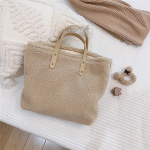 Detailed shot of beige faux shearling tote with brown PU handles and rivet accents