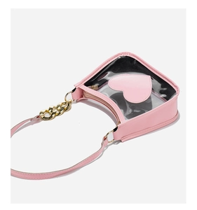 Detail view of pink heart shaped PVC crossbody bag with gold chain and PU leather trim