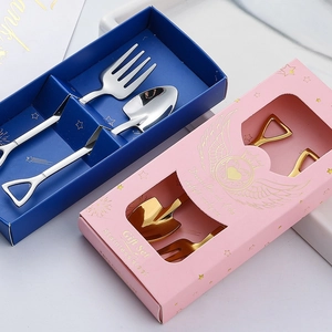 Detail of shovel-shaped gold and silver stainless steel spoon and fork in gift boxes
