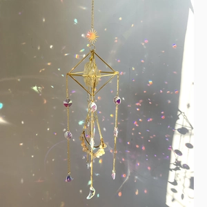 Detail of golden crystal suncatcher showing geometric frame with moon and star charms