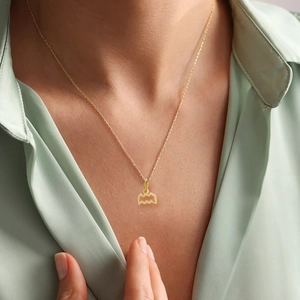 Detail view of the golden geometric wave pendant necklace worn on a female model